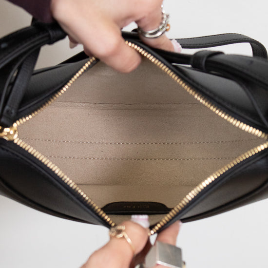 Close-up of a black leather handbag with gold interior and trim.