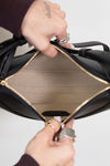 Close-up of a black leather handbag with gold interior and trim.