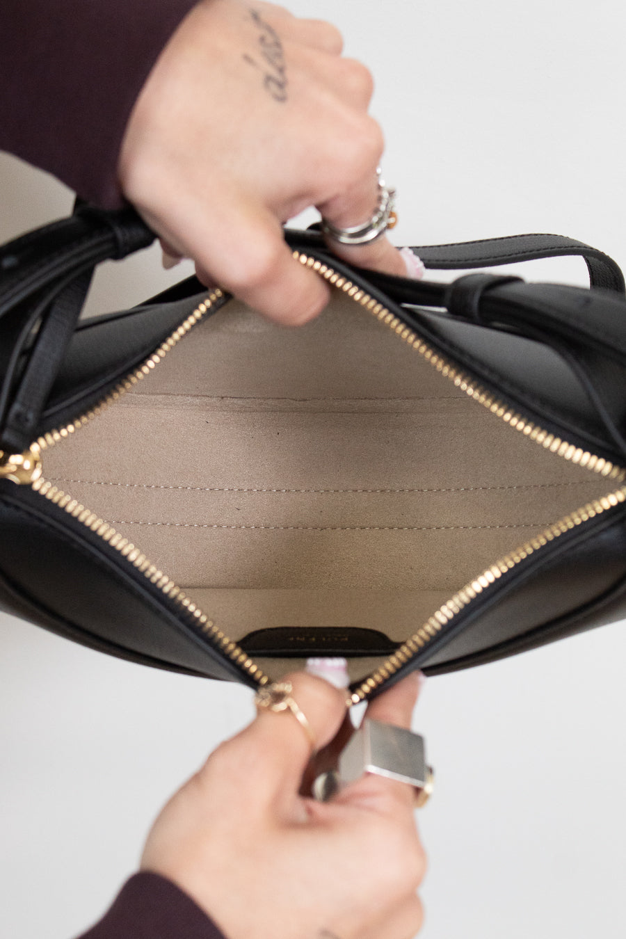 Close-up of a black leather handbag with gold interior and trim.