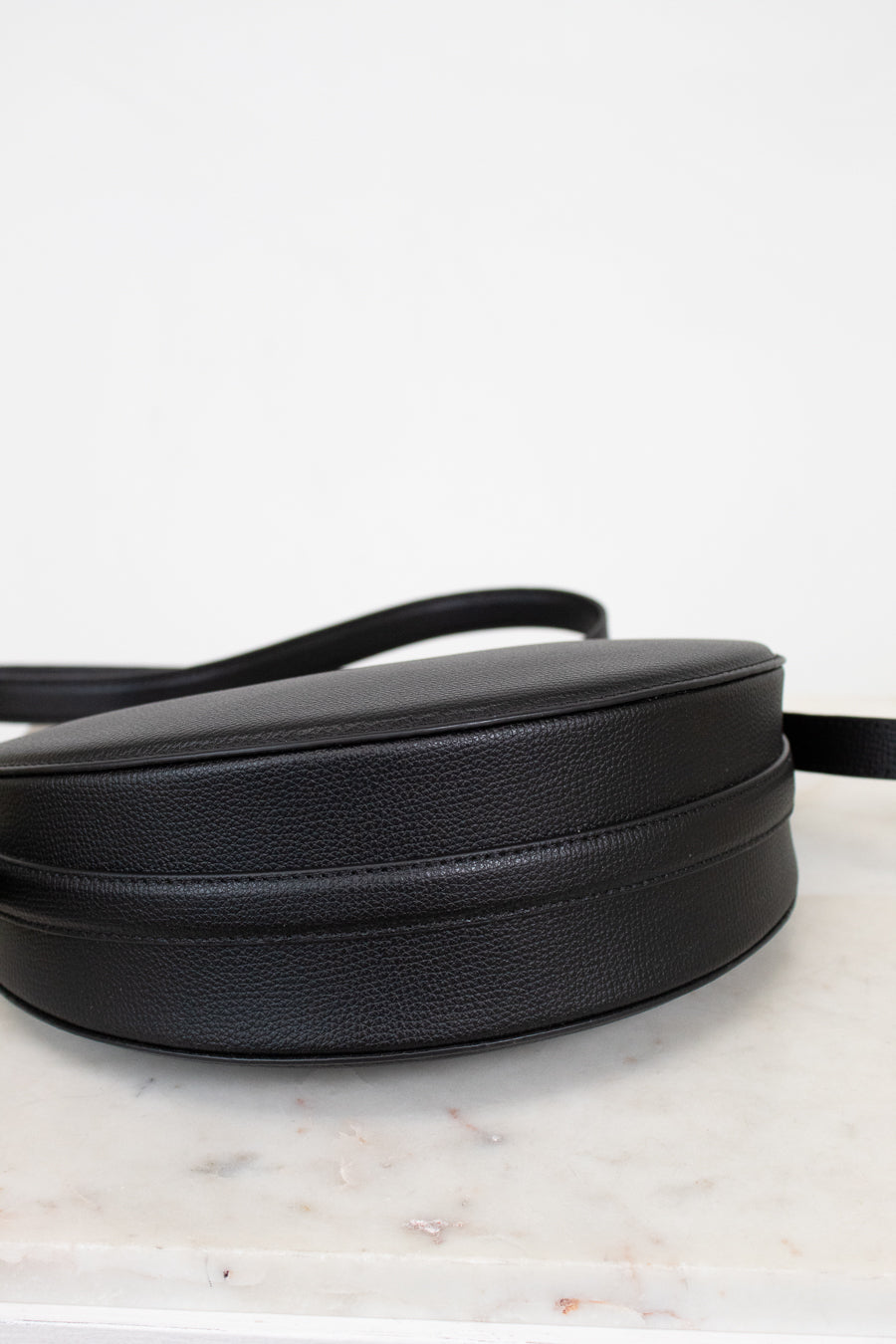 Black leather purse on a marble surface