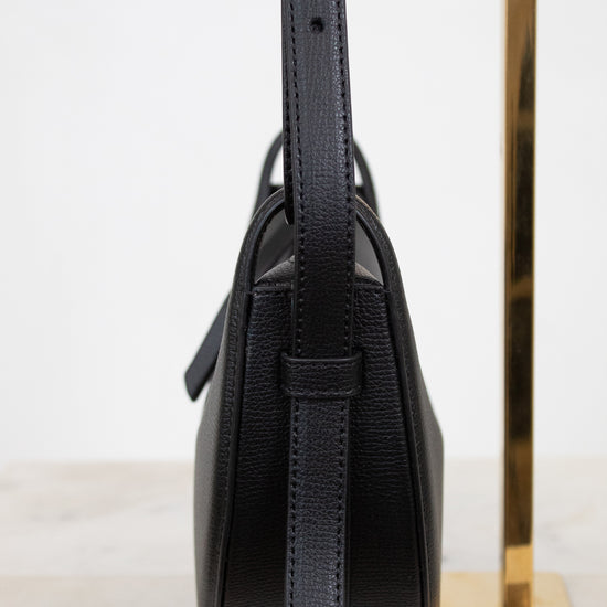 Black leather handbag with a strap on a white background