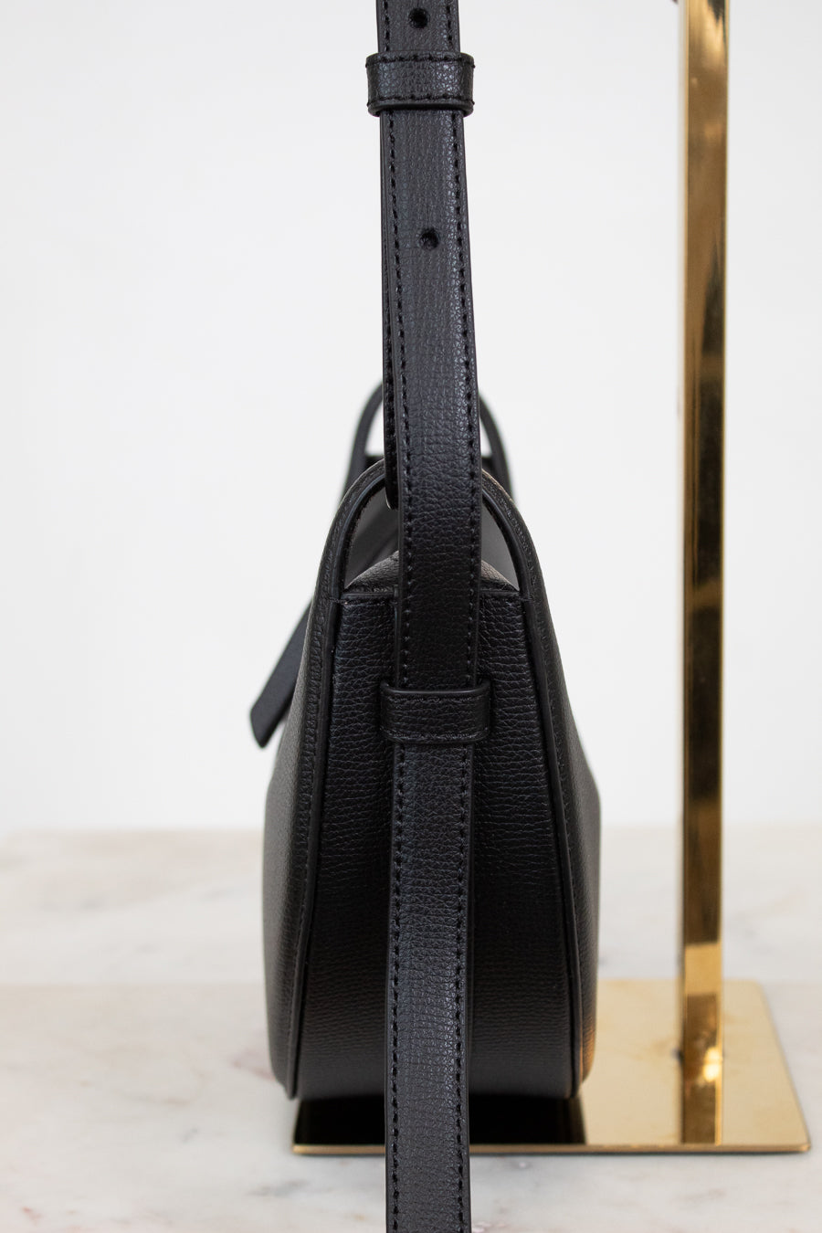 Black leather handbag with a strap on a white background