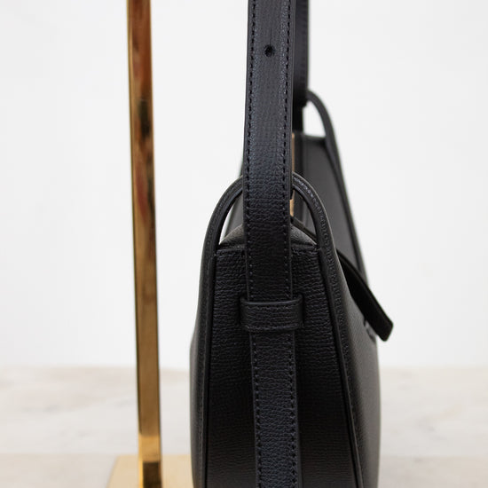 Black handbag with a strap on a white background