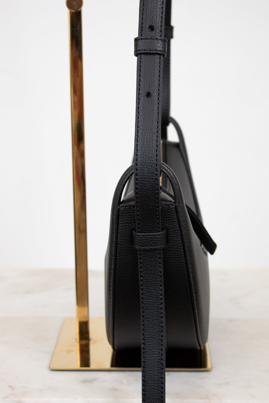 Black handbag with a strap on a white background