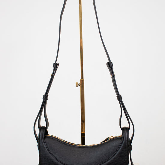 Black leather saddle bag with a strap on a white background