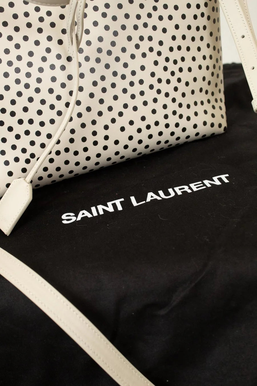 Polka dot handbag with 'Saint Laurent' logo on a black background