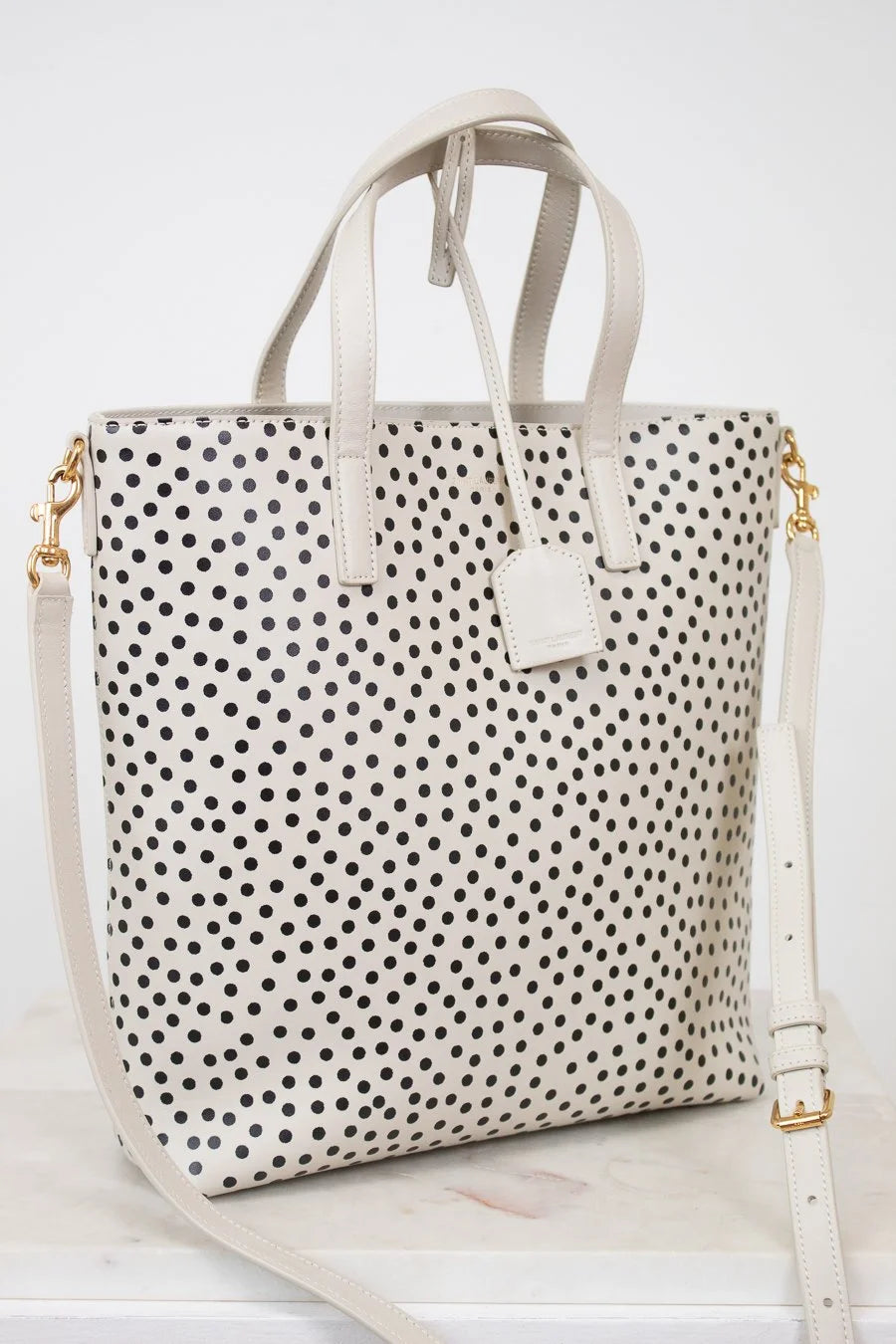 White tote bag with black polka dot pattern on a white background