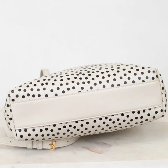 White handbag with black polka dot pattern on a white background