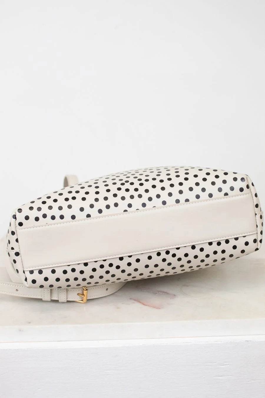White handbag with black polka dot pattern on a white background