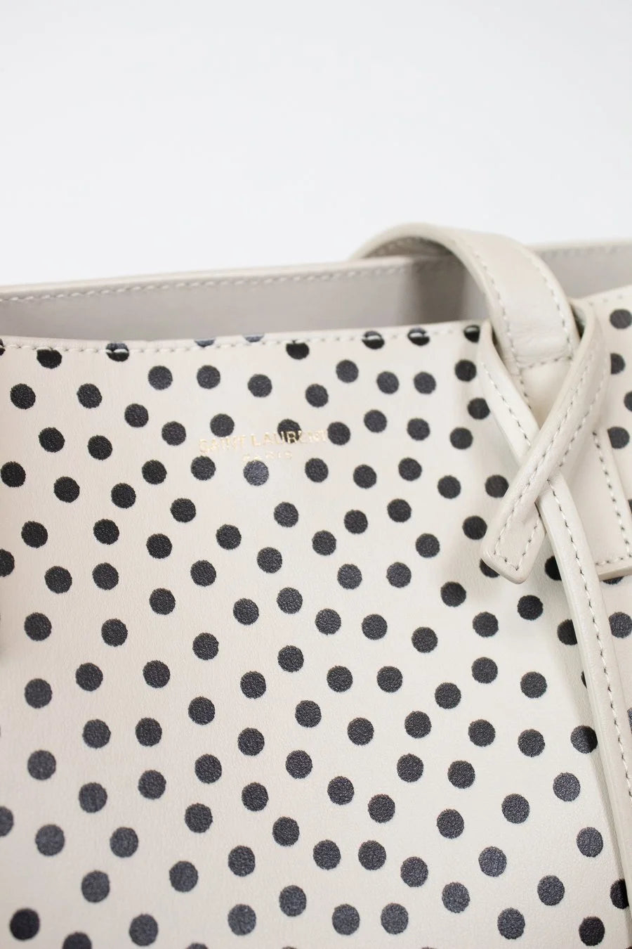 Close-up of a polka dot handbag with a visible brand logo.