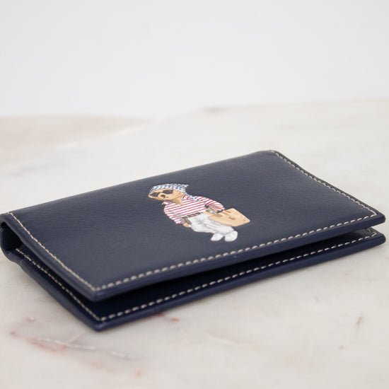 Navy blue wallet with bear design on a light marble surface