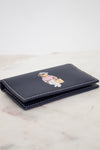 Navy blue wallet with bear design on a light marble surface