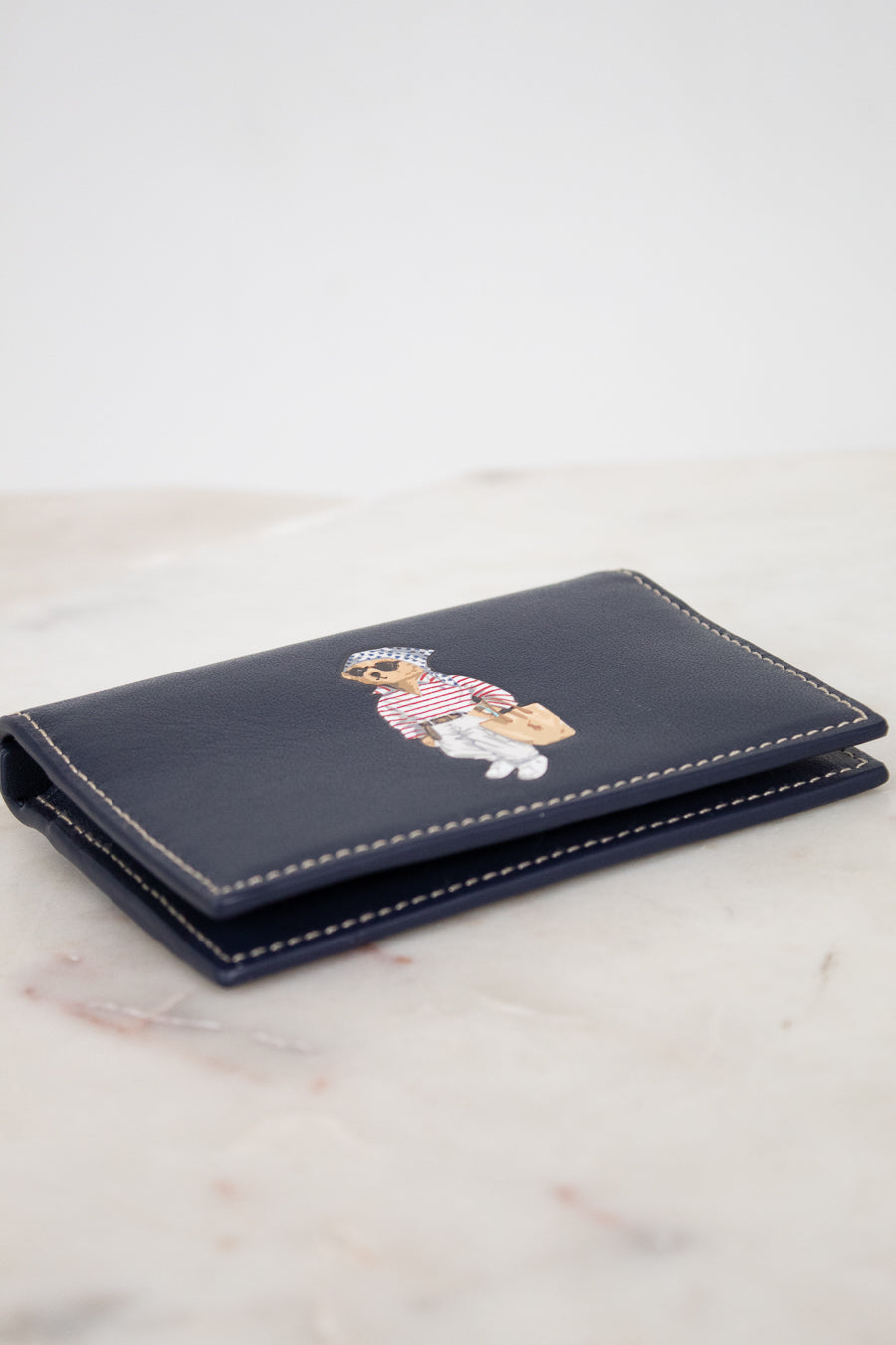 Navy blue wallet with bear design on a light marble surface