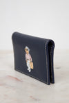 Navy leather cardholder with bear design on a marble surface