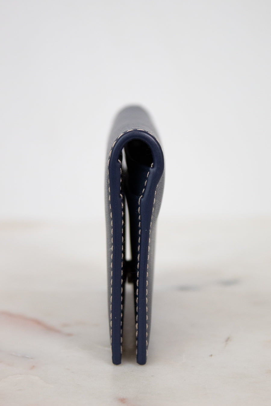 Navy blue leather wallet on a light marble surface