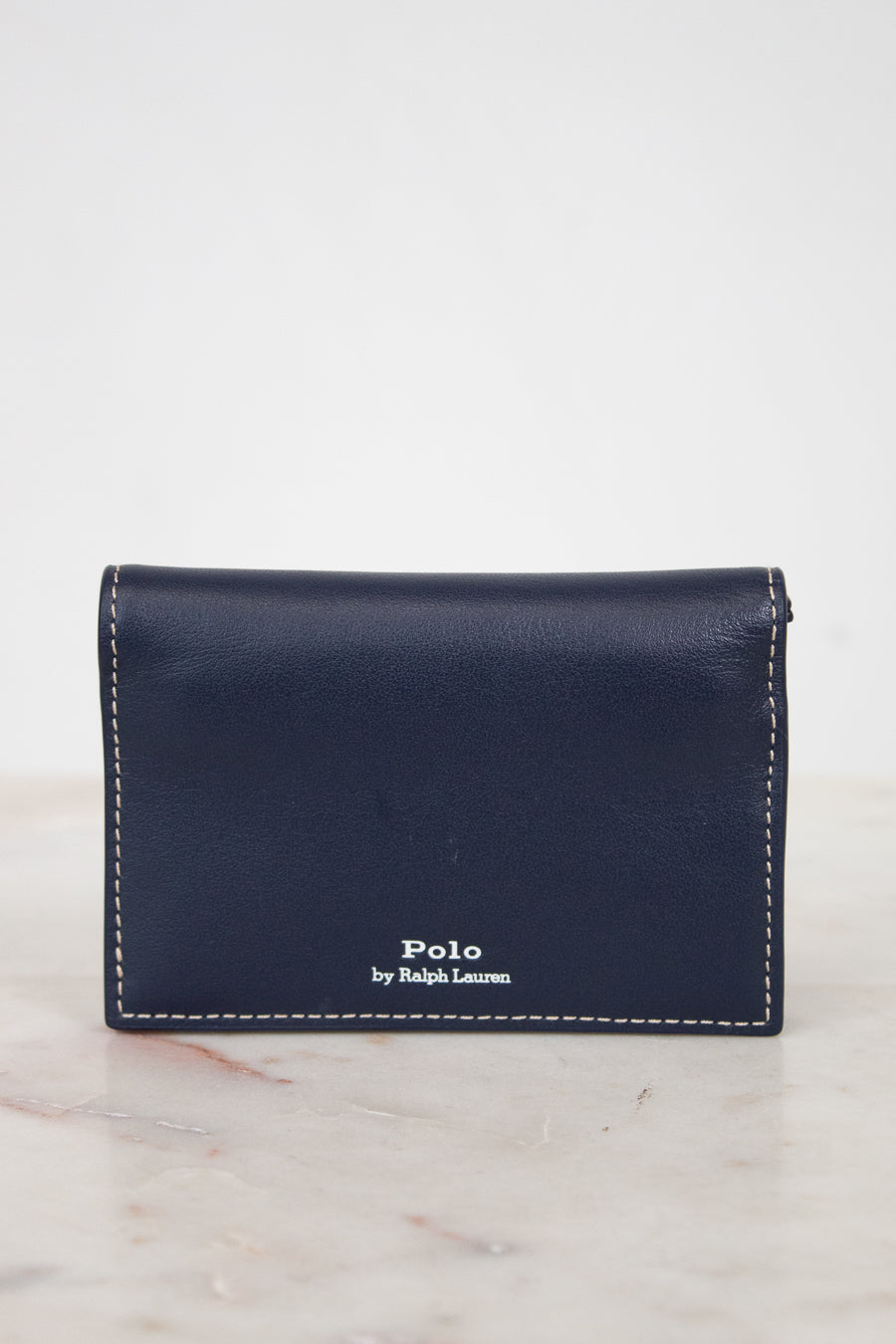 Navy leather wallet with 'Polo by Ralph Lauren' branding on a marble surface.