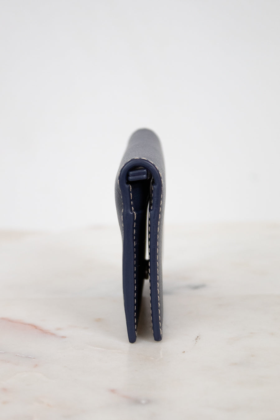Navy blue wallet on a white marble surface