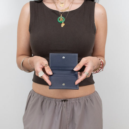 Woman holding a blue wallet against a plain background