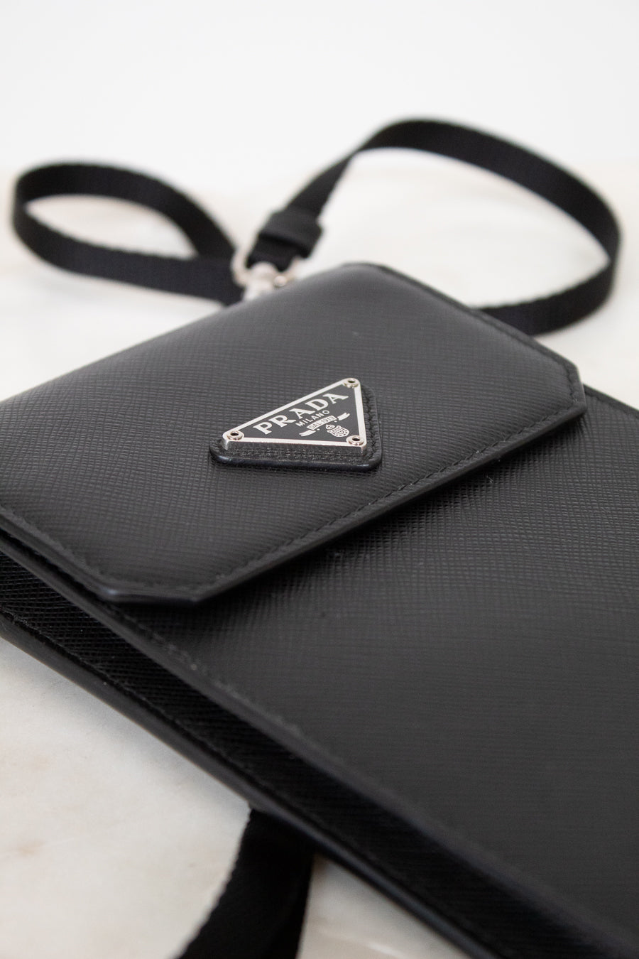 Black Prada handbag with a triangular logo on a white background