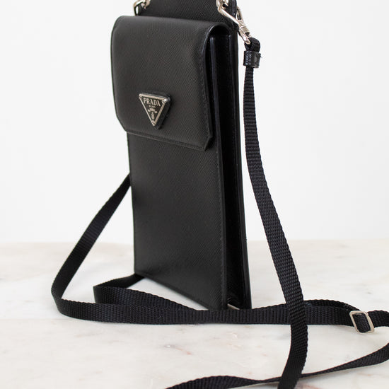 Black crossbody bag with Prada logo on a white background
