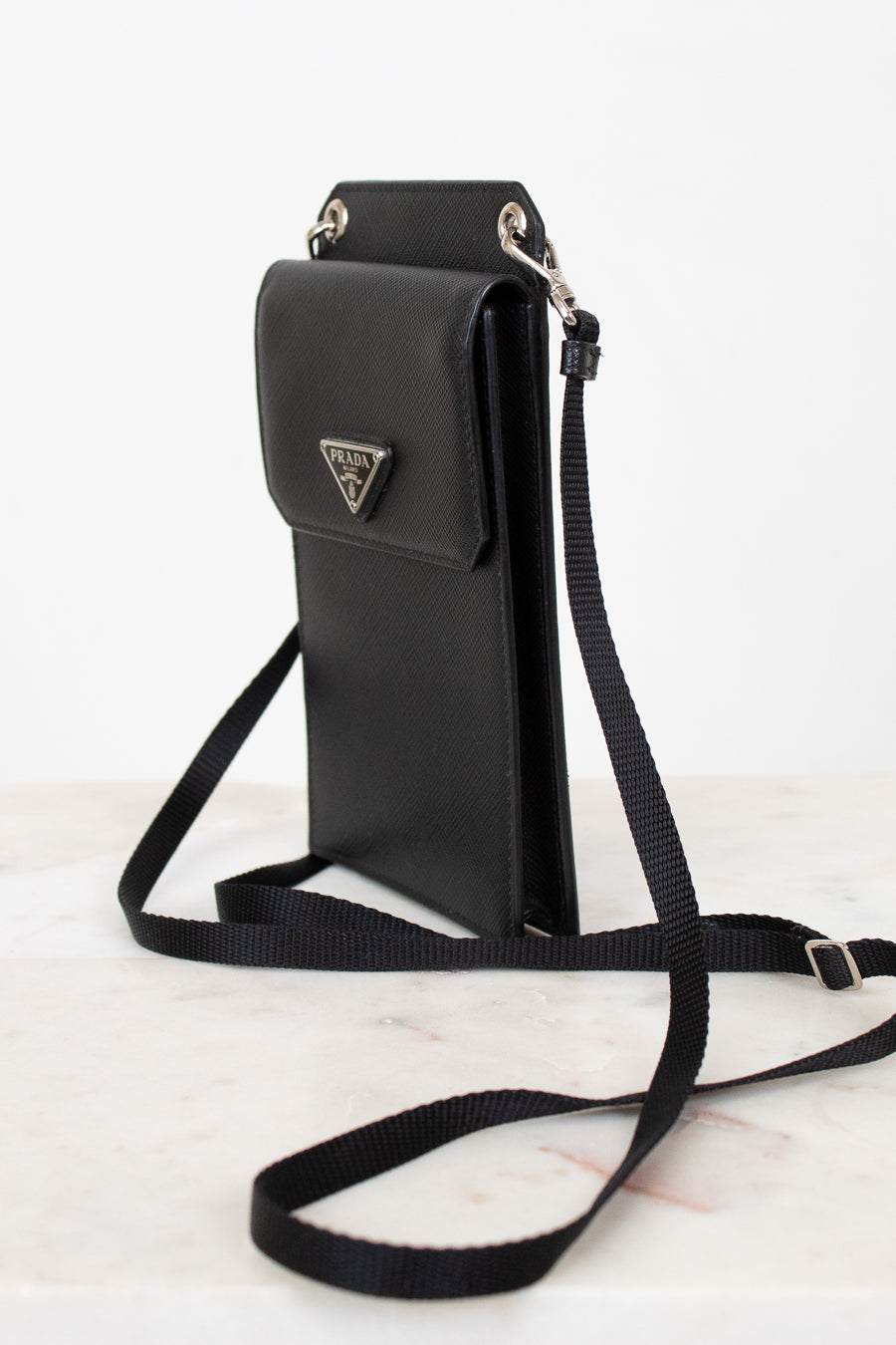 Black crossbody bag with Prada logo on a white background