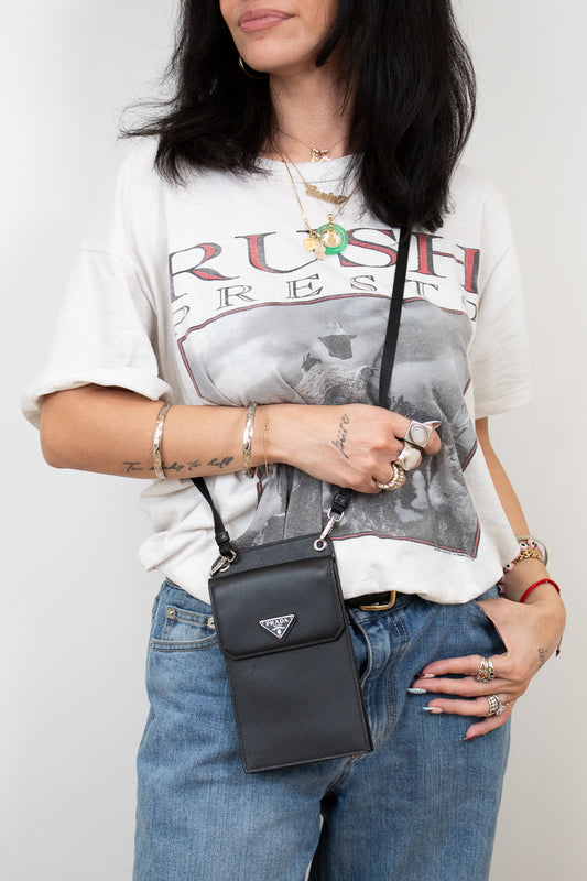 Person wearing a graphic t-shirt and jeans with a black Prada handbag.