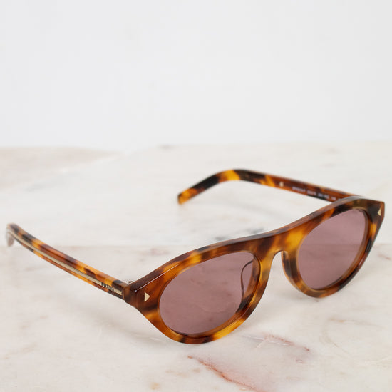 Sunglasses with tortoiseshell frame and brown lenses on a light marble background