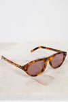 Sunglasses with tortoiseshell frame and brown lenses on a light marble background