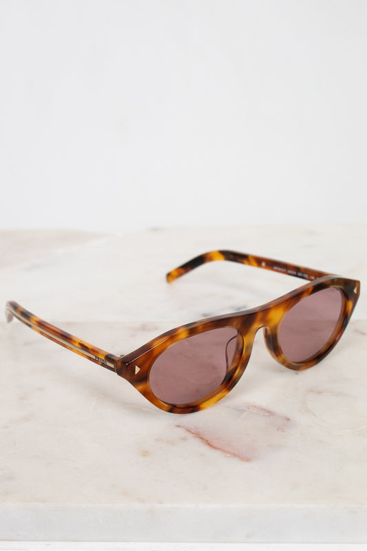 Sunglasses with tortoiseshell frame and brown lenses on a light marble background