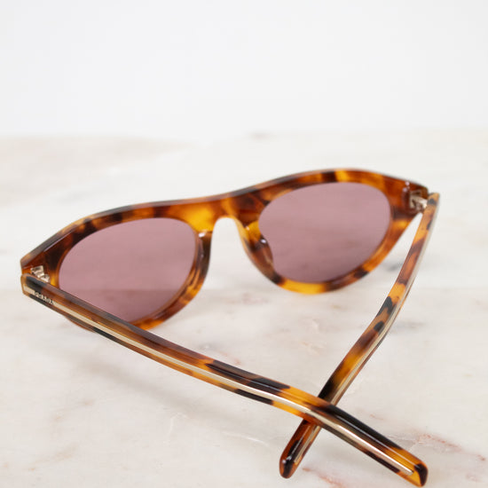 Sunglasses with tortoiseshell frame and brown lenses on a light background