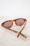Sunglasses with tortoiseshell frame and brown lenses on a light background