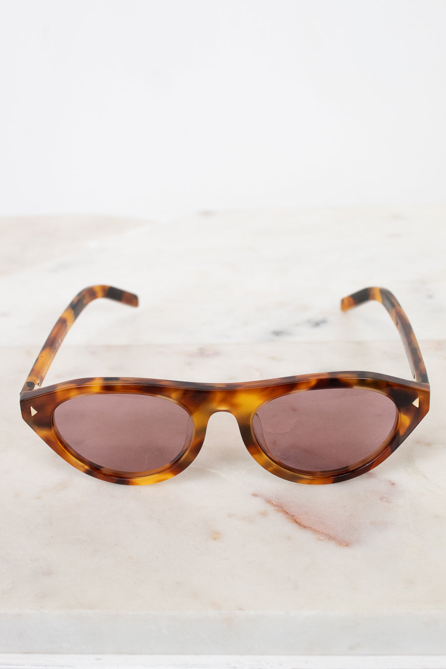 Sunglasses with tortoiseshell frame and brown lenses on a light background