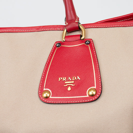 Beige handbag with red accents and Prada logo on a white background