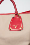 Beige handbag with red accents and Prada logo on a white background