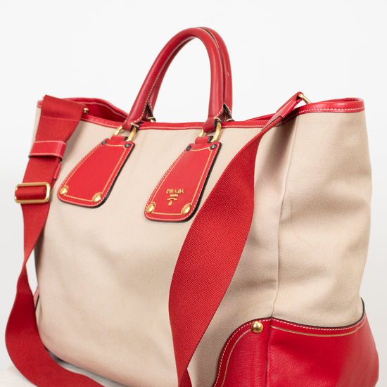 Beige and red handbag with gold accents on a white background