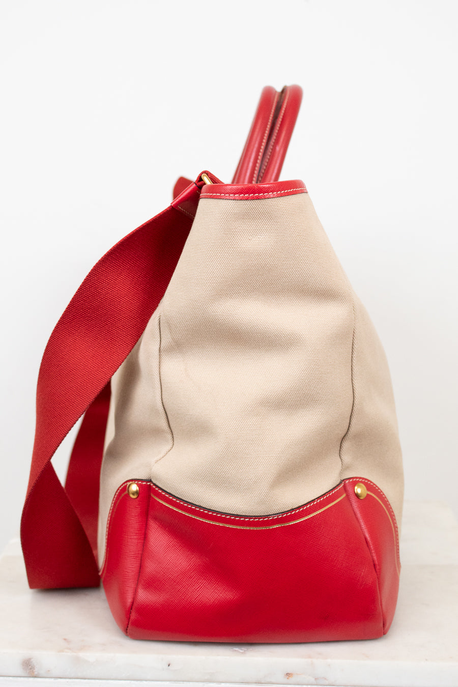 Beige and red handbag with a strap on a white background