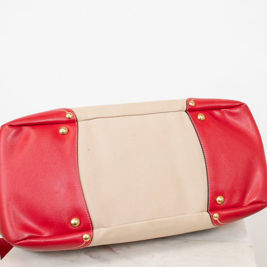 Red and beige clutch bag with gold studs on a white surface
