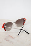 Sunglasses with orange accents on a marble surface