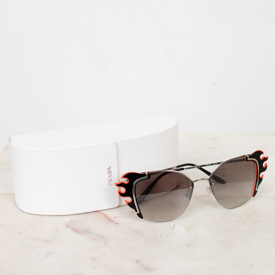 Sunglasses with black and orange accents on a white marble surface