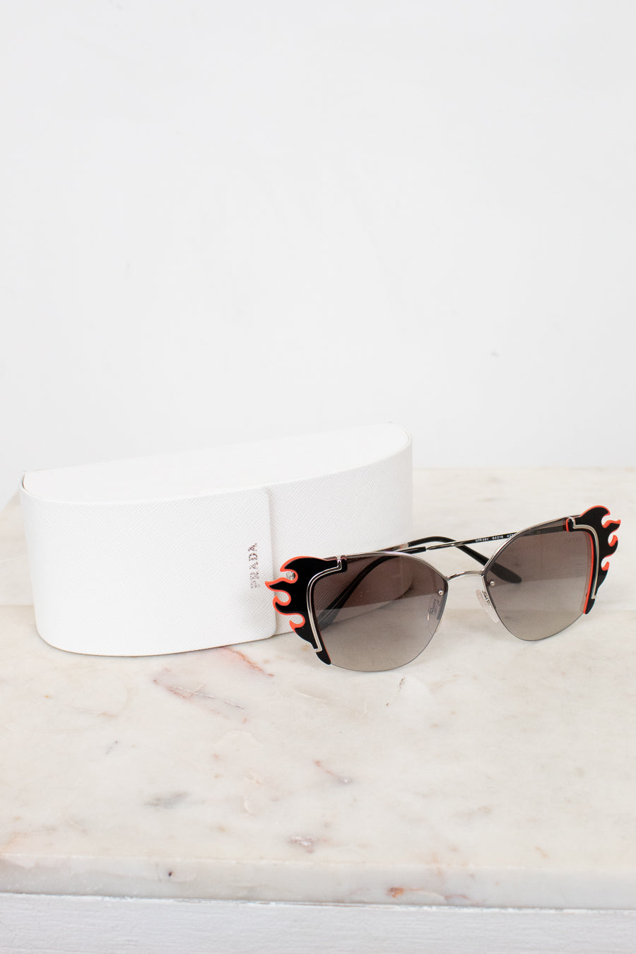 Sunglasses with black and orange accents on a white marble surface