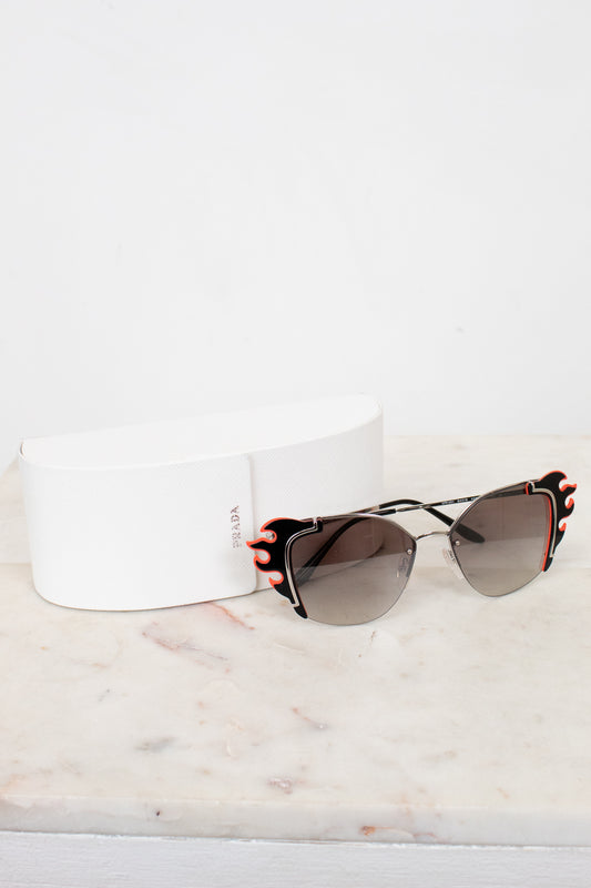 Sunglasses with black and orange accents on a white marble surface