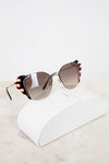 Sunglasses with decorative flame detail on a white surface