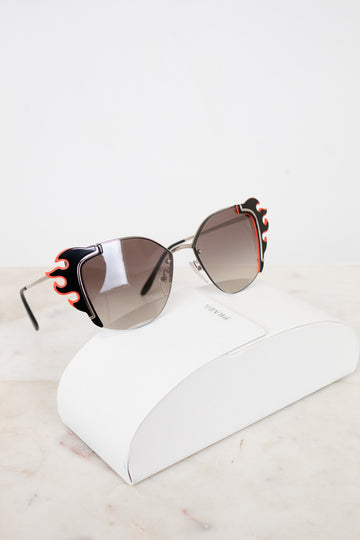 Sunglasses with decorative flame detail on a white surface