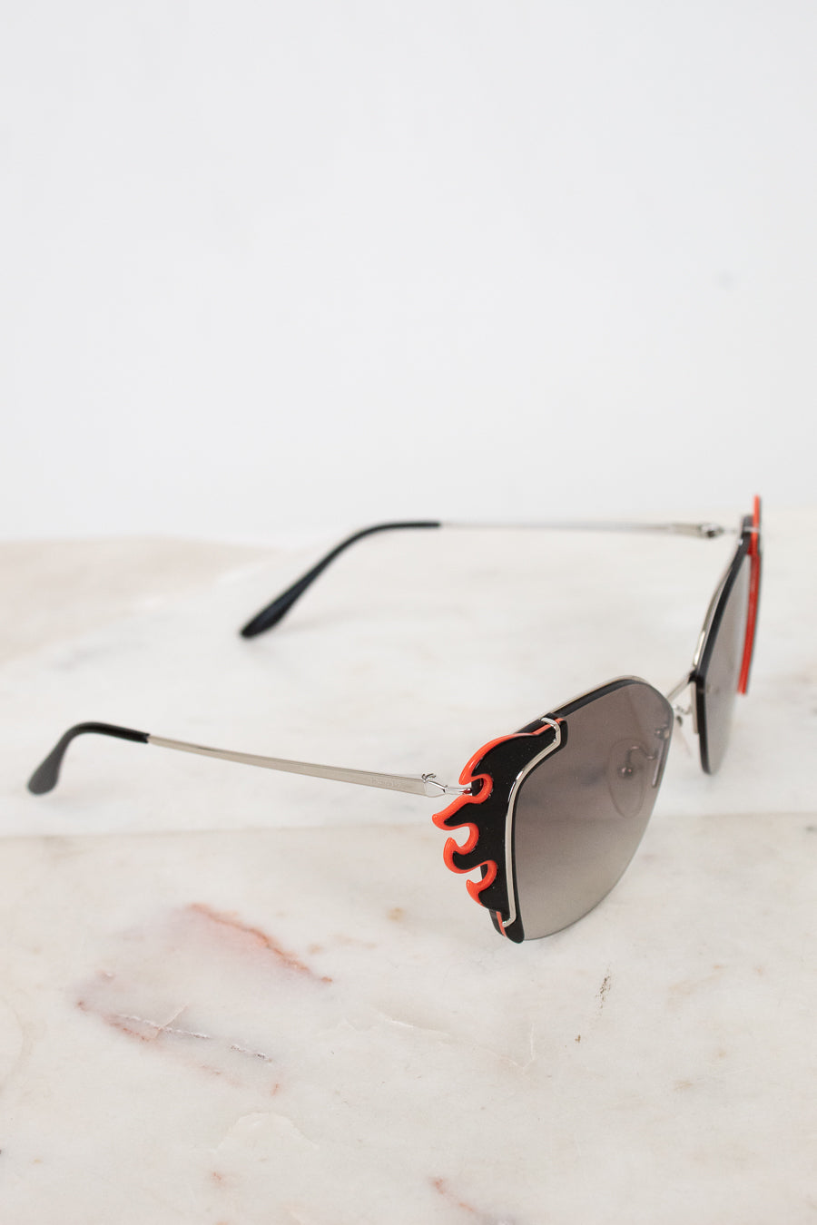 Sunglasses with flame-like design on a marble surface