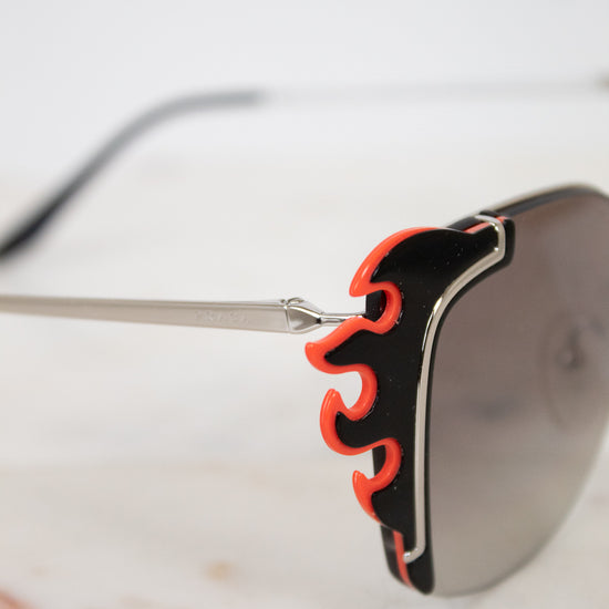Sunglasses with black and orange frame on a marble surface