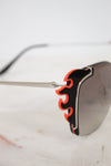 Sunglasses with black and orange frame on a marble surface