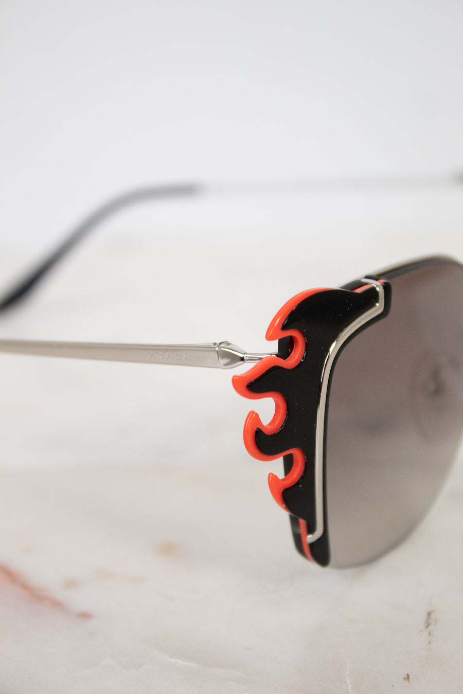 Sunglasses with black and orange frame on a marble surface