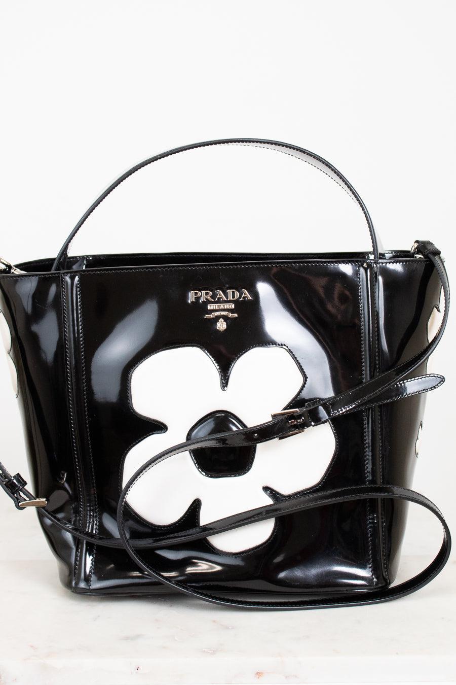 Black Prada handbag with a white flower design on a white background