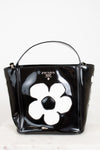 Black Prada handbag with a white flower design on a white background