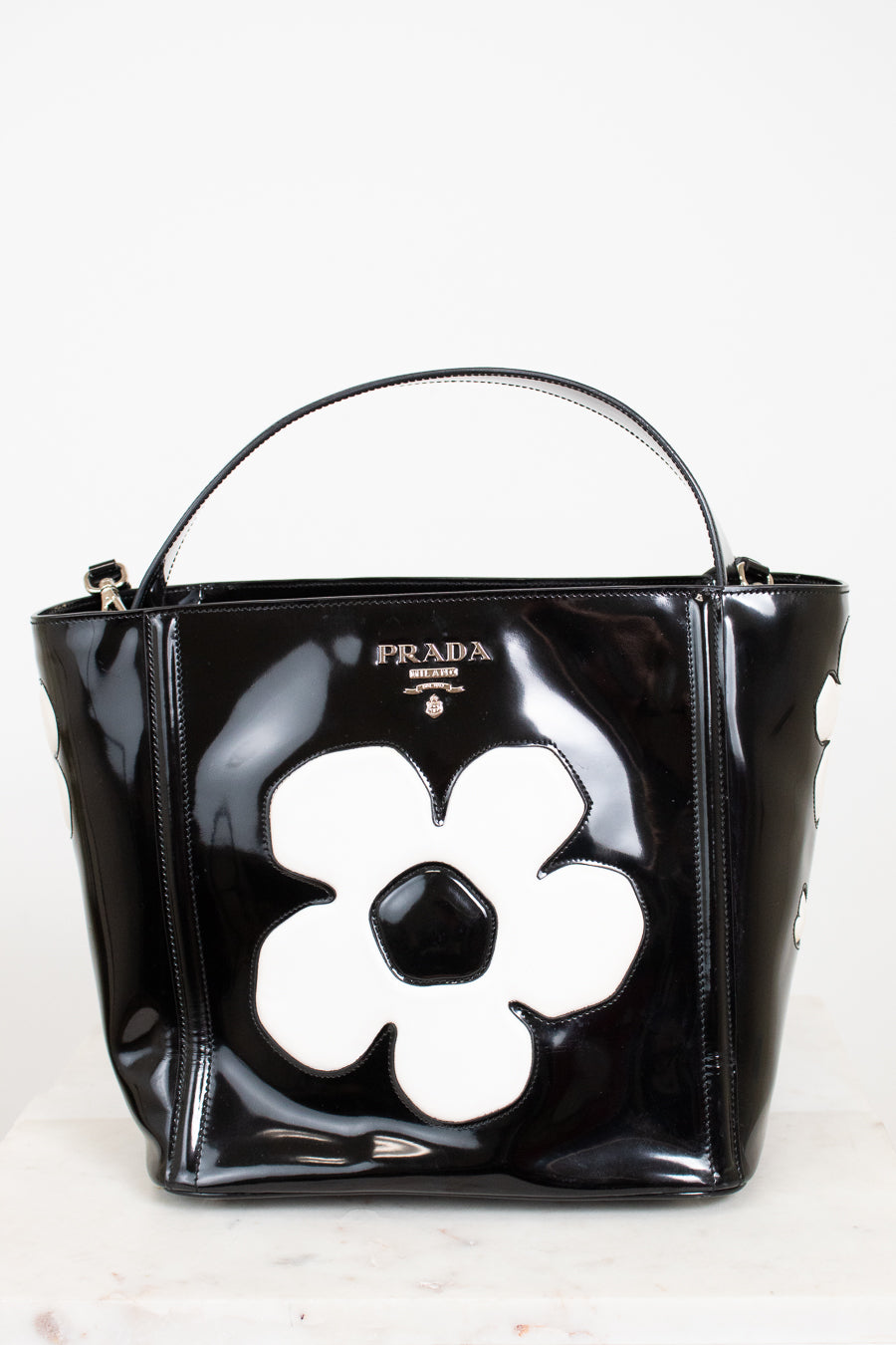 Black Prada handbag with a white flower design on a white background